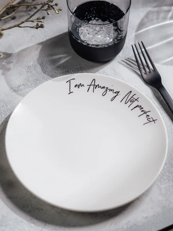 Een Statement bord met de tekst "I am Amazing. Not perfect." op een tafel.