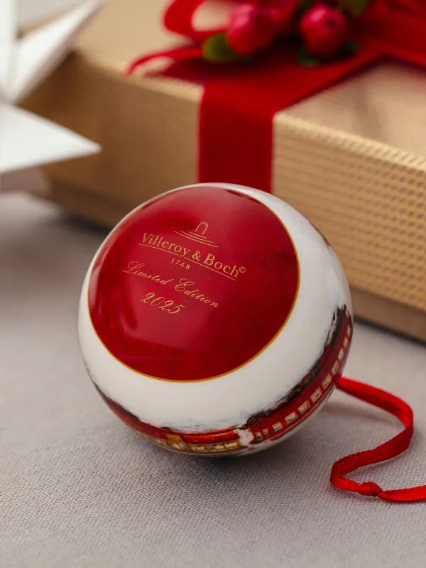 Red and white Christmas ornaments with the text "Villeroy & Boch" next to a wrapped gift and a white paper star. 
