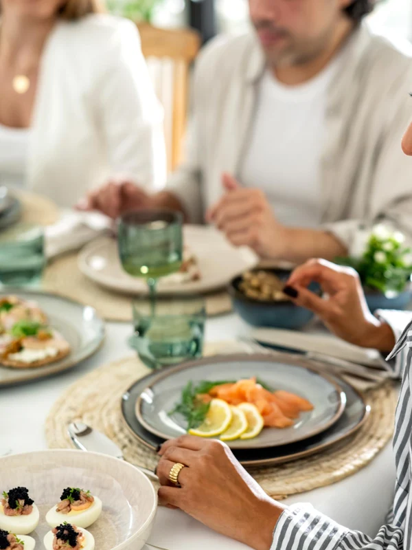 Ein mit beigem Lave Geschirr von like. by Villeroy & Boch gedeckter Tisch mit Menschen, die zusammen essen.
