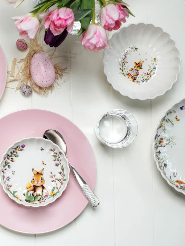 Easter-themed table decoration with decorated Spring Fantasy plates and Rose Garden plates as coasters together with flower arrangements.