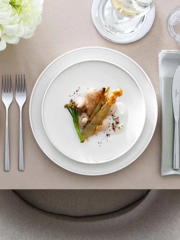 Elegant table decoration with a white Afina gourmet plate, Piemont cutlery and floral decoration.