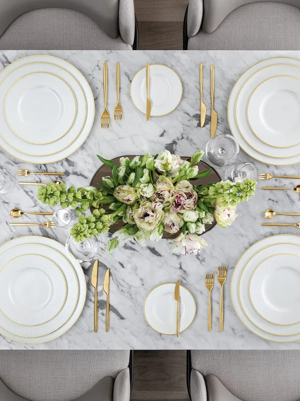 The Villeroy & Boch Chateau Septfontaines placemat in a marble design for six people, elegantly decorated with white and gold crockery, cutlery and glasses. A flower arrangement with white and pink blossoms decorates the centre, accompanied by small bowls of fruit and nuts.