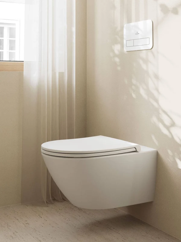 Minimalist bathroom with a black Collaro back-to-wall bath, dark walls, two round wall lights and a green towel. Shadows and a small plant add texture to the scene