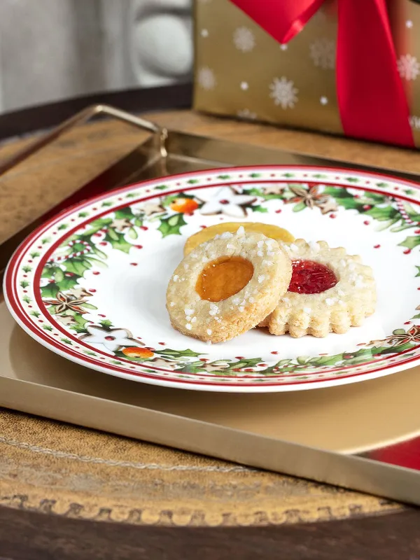 Christmas biscuits on a festive Winter Bakery Delight plate with a gift in the background.
