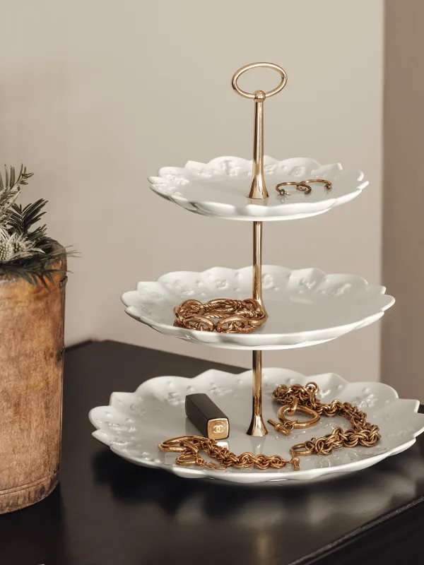 Three white porcelain plates on a tired stand with gold accents