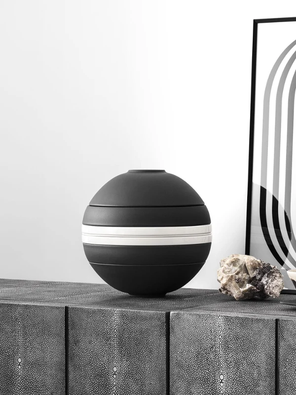 Op een dressoir staat een zwart-witte La Boule Stripe van Villeroy & Boch.