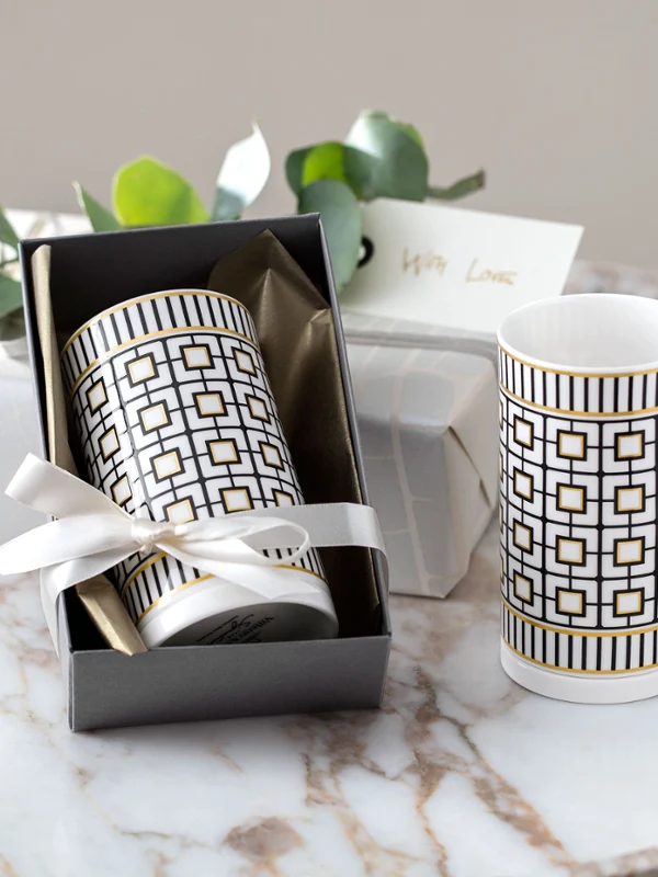 Twee MetroChic vazen in een geschenkdoos, vergezeld van kaarsen en een kaartje op een marmeren tafel.