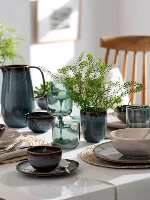 Ein schön gedeckter Esstisch mit Lave-Geschirr, Gläsern, Grünpflanzen und frischen Backwaren in einer modernen Küche von Villeroy & Boch.
