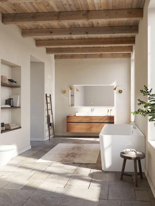 Large bathroom with a white bath from the Collaro collection A spacious bathroom in a modern design with a bath, a wall-mounted toilet, a large washbasin, a wooden ceiling and a large window. Shelves with books and decorations together with a plant complete the design.