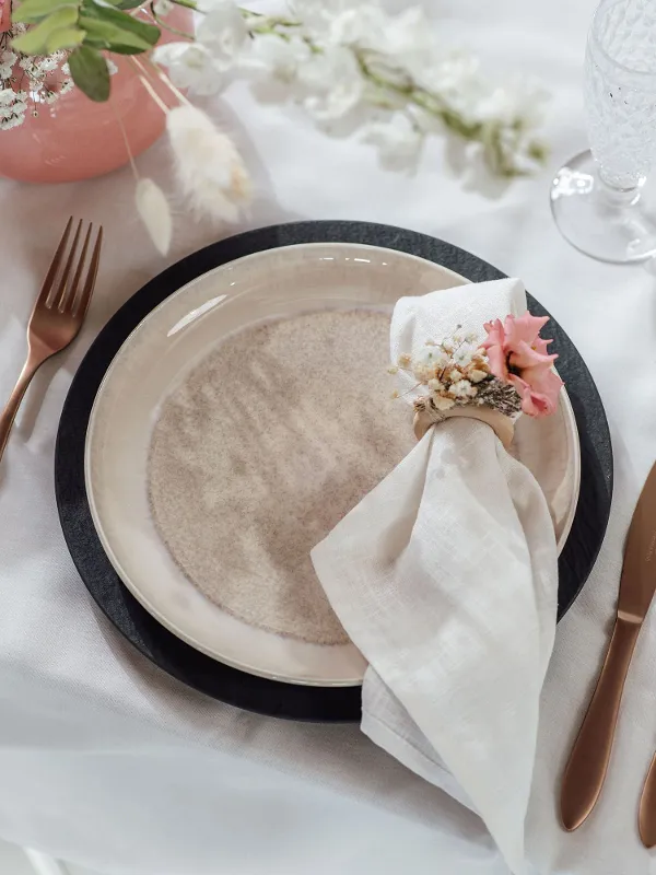 Table decoration with a Villeroy & Boch beige Perlemor dinner plate, copper-coloured Manufacture cutlery and flowers.