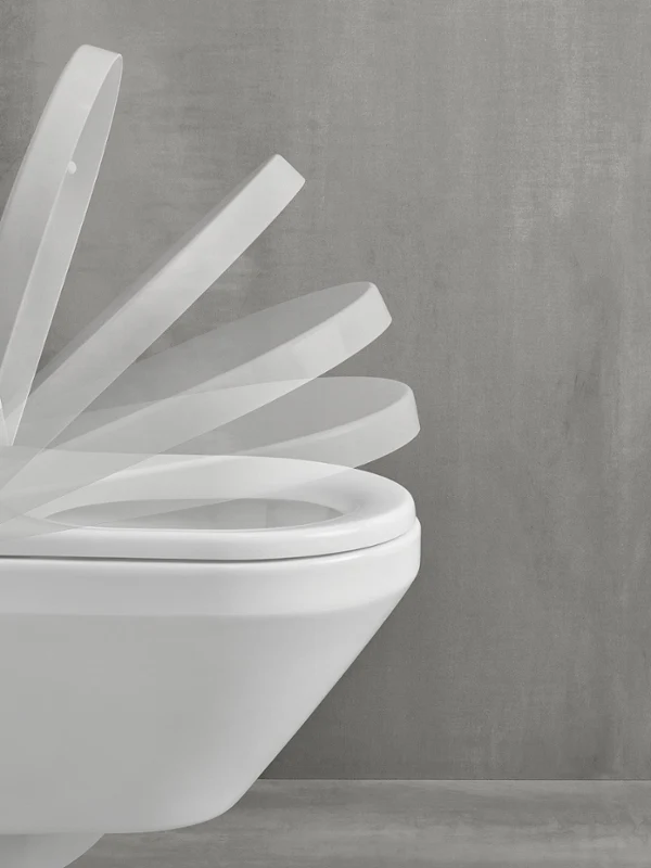 SoftClosing function on a toilet lid Toilet with grey wall background, against which the action of opening and closing the lid can be seen.