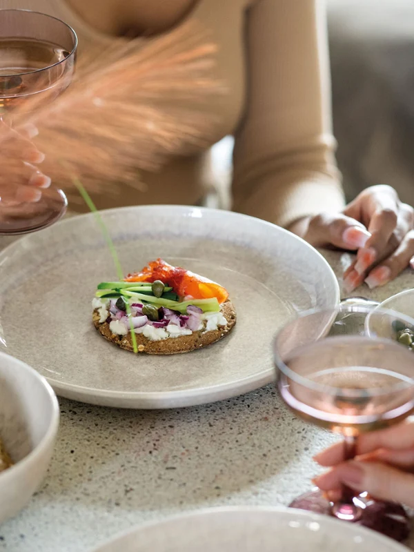 Eine Gruppe von Leuten, die an einem Tisch sitzen und Knäckebrot von Perlemor Tellern essen.