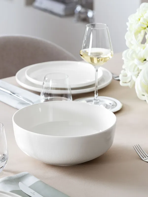 Large empty Villeroy & Boch Afina serving bowl on a laid table, with flowers in the background.
