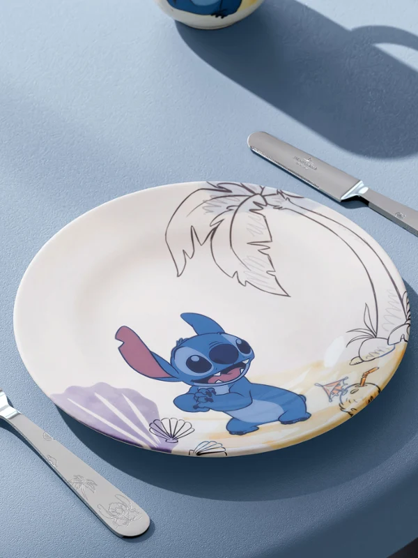 Un plato, un tenedor y un cuchillo de la colección Disney Stitch sobre una mesa azul. Un plato con una ilustración, un tenedor y un cuchillo de la colección Disney Stitch sobre una mesa azul con textura.