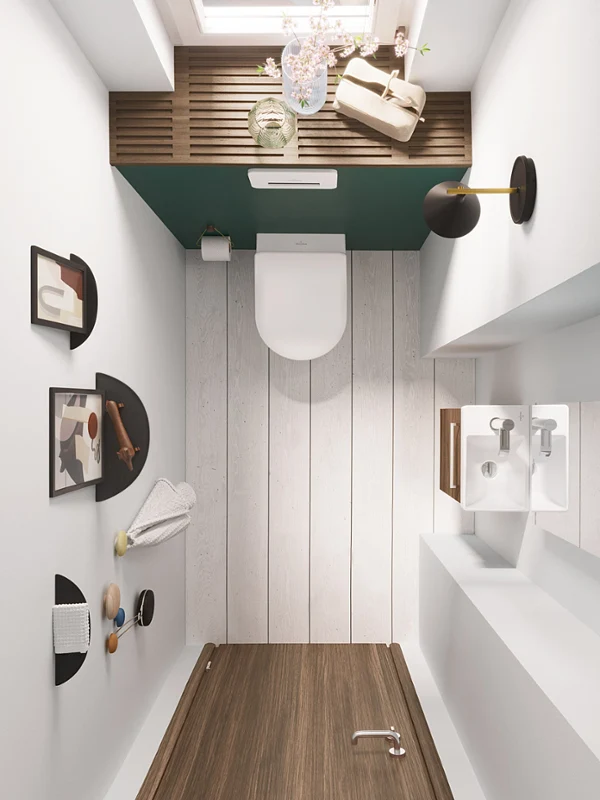 Top view of a bathroom with a toilet and a washbasin with a mirror from the Avento collection Top view of a small bathroom with a wall-mounted washbasin, a mirror, a toilet and modern decor with abstract art. The room has a white floor, white walls and a wooden door.