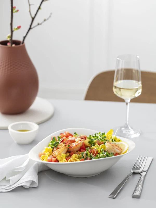 Biała miska Vapiano z makaronem i białe wino Biała miska Vapiano wypełniona daniem z makaronu, kieliszek białego wina i mniejsza miska na stole w jadalni.