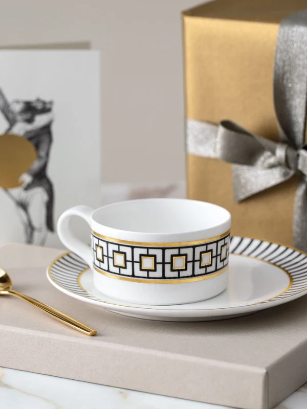 Eine goldene MetroChic Teetasse mit Untertasse auf einem Marmortisch.