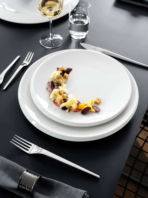 Elegantly laid dining table with NewMoon plates and wine glasses.