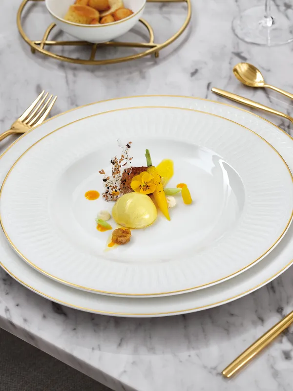Elegant table setting with Villeroy & Boch crockery from the Château Septfontaines collection, golden cutlery and glasses.