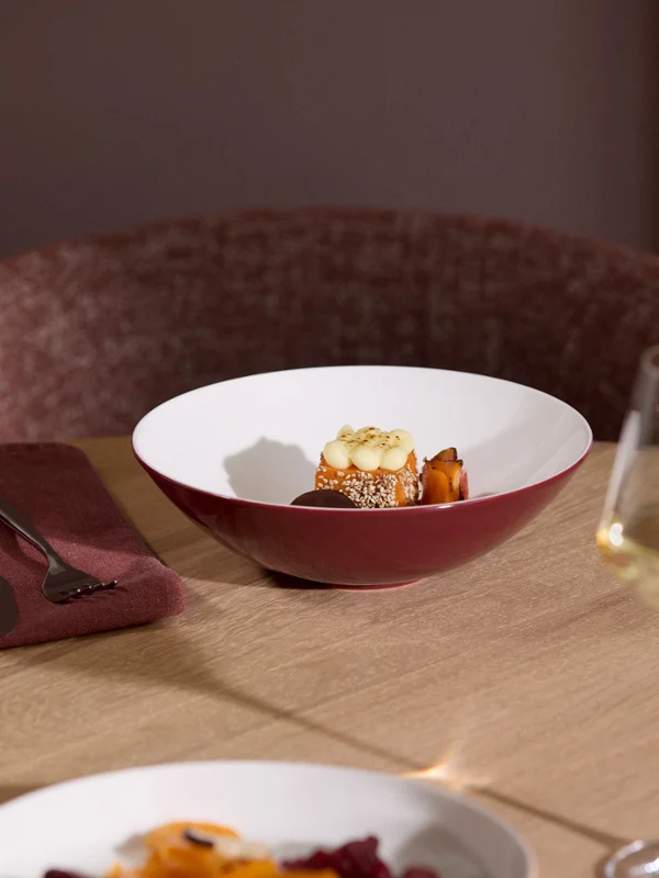 La Boule Kyoto food table A set table with a glass of white wine, cutlery, a water glass, and a La Boule Kyoto bowl filled with food, all arranged on a wooden platter.