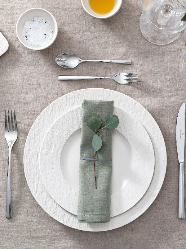 A table set with Villeroy & Boch white Manufacture plates, eucalyptus leaves and cutlery.