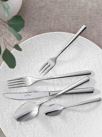 Elegant table decor with modern Piemont flatware and decorative green on a neutral table cloth.