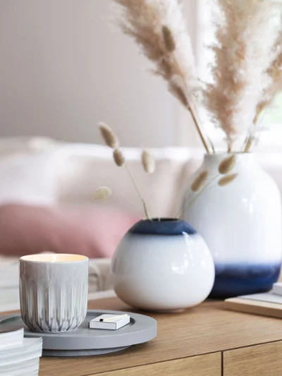 A living room with white and blue Lave vases, books and a Perlemor scented candle.