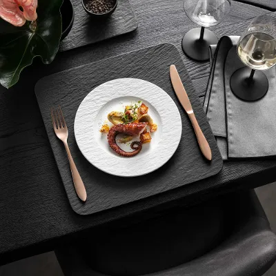 Elegant dining room with gourmet food, wine and modern Manufacture crockery in black and white on a dark wooden table.