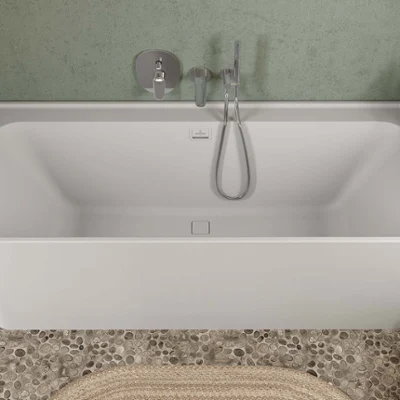 Boho-style bathroom washstand Modern bathroom with a Collaro double washstand in light-coloured wood and a green Antao surface-mounted washbasin, a large rectangular mirror and a tall coordinating Collaro cabinet. Pebble flooring and minimalist decor complete the look.