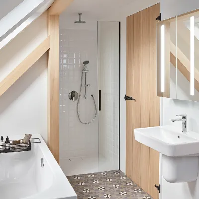 Modernes Bad mit Dusche, Waschbecken und Badewanne unter einer Dachschräge Ein modernes Badezimmer mit ebenerdiger Dusche, weißem Waschbecken, Spiegelschrank und Badewanne unter einer Dachschräge. Der Boden ist mit einem geometrischen Muster gefliest. Eine Holztür und Balken betonen den Raum.