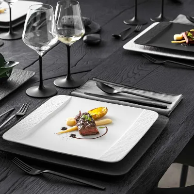 Manufacture crockery in black and white with a main course served on a black table, beside glasses with black stems from Villeroy & Boch.