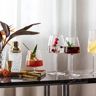 Various cocktails in elegant MetroChic glasses on a marble table next to a plant.