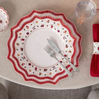 A festively laid table A festively laid table with red-and-white patterned crockery, a red napkin, and a knife and fork on a round table.