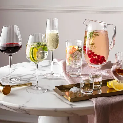 Glasses and jugs from the Villeroy & Boch Rose Garden collection on a round marble table with drinks and citrus fruits.