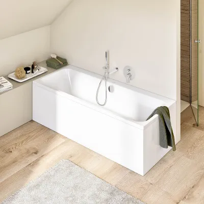 Weiße rechteckige Architectura Badewanne mit grünem Handtuch Ein modernes Badezimmer mit einer weißen rechteckigen Architectura Badewanne, über deren Rand ein grünes Handtuch hängt. Der Raum hat einen hellen Holzboden und eine beige Wand. Neben der Badewanne steht ein Regal mit Toilettenartikeln.