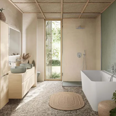 WC im Boho-Badezimmer Wandhängendes Villeroy & Boch Antao WC in Grün vor einer strukturierten beigen Wand und Steinboden. An der Seite hängen Handtücher.