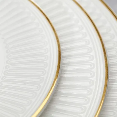 Three interlocking white porcelain plates with gold rims and intricate patterns.