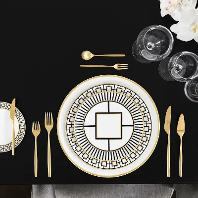 Elegant dining table decoration with gold-patterned MetroChic plates, gold flatware, crystal glasses viewed from above.