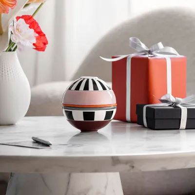 La petite Boule Memphis from Villeroy & Boch and two wrapped gifts stand on a marble table, with a vase of flowers in the background.