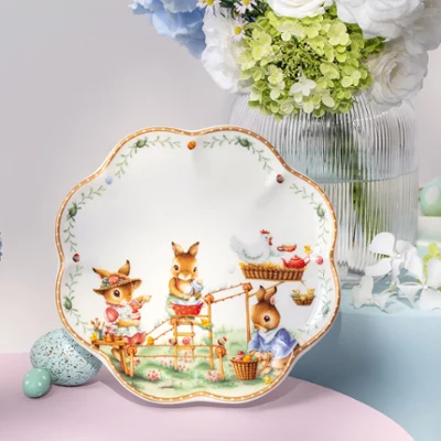 Decorative Annual Easter Edition plate with animal illustrations Decorative Annual Easter Edition plate with animal illustrations, displayed among vases of flowers and pastel-colored eggs on a table.