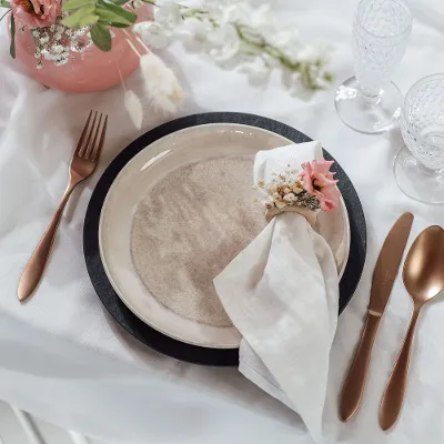 Table decoration with a Villeroy & Boch beige Perlemor dinner plate, copper-coloured Manufacture cutlery and flowers.