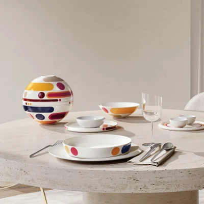 La Boule Miami on an oval stone table Oval stone table with modern colourful La Boule Miami. Shown assembled, then in individual pieces, arranged at a large window with a chair.
