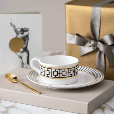 MetroChic Teetasse mit Untertasse auf Marmortisch Eine goldene MetroChic Teetasse mit Untertasse auf einem Marmortisch.