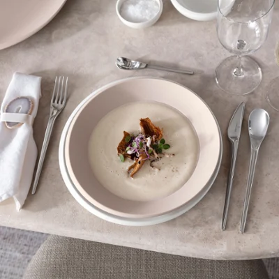 A table set with Villeroy & Boch NewMoon plates and cutlery with cream soup.