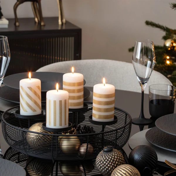 Four striped candles are burning Four striped candles are burning on a festively laid dining table, which is set with plates, glasses and festive decorations.