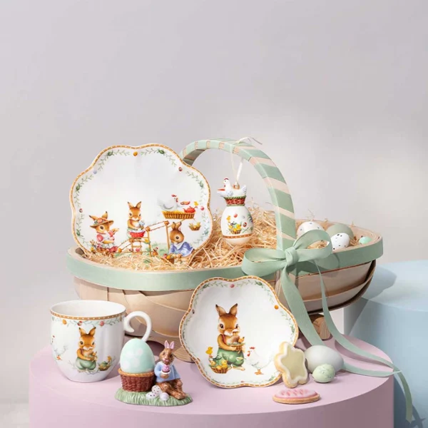 A decorative Annual Easter Edition 2026 basket A decorative Annual Easter Edition 2026 basket with bunny-themed plates, cup, figurine, cookies, eggs, and a green ribbon.