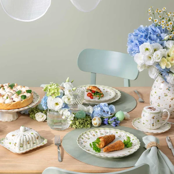 A Easter Delight dining table set for four with Easter Delight decorations, pastel tableware, and plates of food arranged neatly.