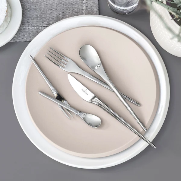 NewMoon table cutlery on a beige plate Villeroy & Boch NewMoon table cutlery on a beige plate on a grey background.