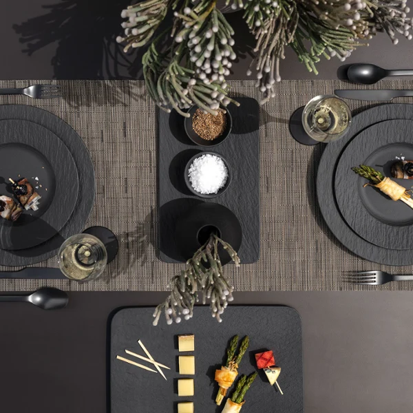 A modern dining table with Manufacture plates A modern dining table with two place settings, each with Manufacture plates, flatware, napkins, appetizers, and glasses.