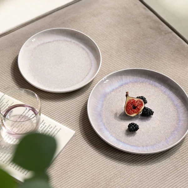 Perlemor Sand & Like Pearl – Natural Details, Timeless Beauty A close-up table view featuring Villeroy & Boch’s Perlemor Sand plates in soft beige tones and a Like Pearl water glass. One plate is styled with a halved fig, adding a subtle, natural accent to the elegant table arrangement. The scene highlights organic textures and calm, harmonious design.
